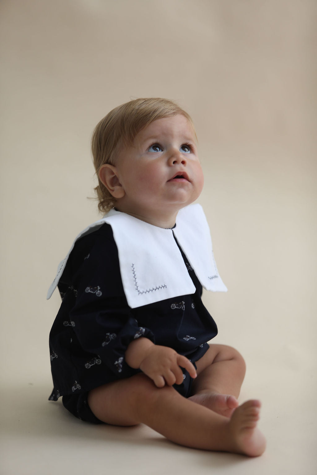 Blonde Boy sat on ride on car wearing blue sweater